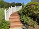Exterior staircase with white railing, leading up into a lush green yard with colorful foliage at 3076 Harris Mill Ct, Duluth, GA 30096