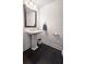 This half bath features a pedestal sink, dark floors, and a wood-trimmed mirror at 227 Atley Pl, Alpharetta, GA 30009