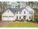 Charming two-story home with a well-manicured lawn, three-car garage, and attractive architectural details at 4057 Watkins Glen Dr, Woodstock, GA 30189