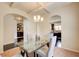 Open dining room with elegant lighting, glass table and view to kitchen at 2580 Brittany Park Cv, Ellenwood, GA 30294