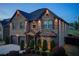 Exterior shot of a two-story home with elegant outdoor lighting at twilight at 2580 Brittany Park Cv, Ellenwood, GA 30294