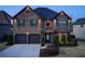 Home exterior at dusk featuring stone facade, two-car garage and manicured landscaping at 2580 Brittany Park Cv, Ellenwood, GA 30294