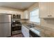 Kitchen featuring stainless steel appliances, granite countertops, and white cabinets with natural light at 761 Caron Nw Cir, Atlanta, GA 30318