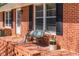Inviting front porch with brick flooring, bench seating, flower pots and freshly painted trim at 4162 Brownlee Dr, Tucker, GA 30084