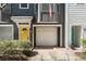 Close-up exterior of gray townhouse featuring garage, yellow front door, and well-kept landscaping at 951 Glenwood Se Ave # 3104, Atlanta, GA 30316