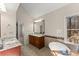 Bright bathroom featuring a soaking tub, granite countertops, and views of the wooded landscape at 400 Surveyors Pt, Suwanee, GA 30024