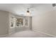 A bright bedroom with a ceiling fan, neutral paint, and a series of windows showcasing a beautiful tree-filled view at 400 Surveyors Pt, Suwanee, GA 30024