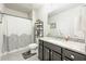 Bathroom featuring a shower with a paisley curtain, gray vanity with marble counters, and a decorative shelving unit at 4030 Amberhill Cir, Cumming, GA 30040