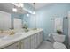 Light blue bathroom features a double sink vanity and brass fixtures, toilet, and white tile flooring at 2049 Castleway Ne Ln, Atlanta, GA 30345
