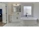 This bathroom features white marble floors, a freestanding tub, a vanity with black hardware, and a frosted glass window at 2546 Summer Song Way, Buford, GA 30519