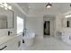 This bright bathroom features double vanity sinks, black hardware, a freestanding soaking tub, and marble floors at 2546 Summer Song Way, Buford, GA 30519