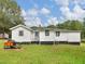 View of the home's back exterior, set on a sprawling green lawn with a chicken coop at 1202 Coan Dr, Locust Grove, GA 30248