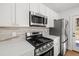 A stainless steel gas range and microwave are highlighted in this modern kitchen with white cabinets and countertops at 1385 Benteen Se Way, Atlanta, GA 30315