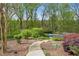 Lush backyard with mature trees, a stone walkway, and a glimpse of a refreshing swimming pool at 1724 Ridge Valley Nw Ct, Atlanta, GA 30327