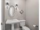 Elegant powder room featuring pedestal sink, oval mirror, and decorative sconce lighting at 1724 Ridge Valley Nw Ct, Atlanta, GA 30327