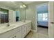 Bathroom featuring a dual sink vanity and large mirror, with a view into an adjacent bedroom at 981 Cranbrook Glen Ln, Snellville, GA 30078