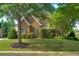 Charming two-story brick home with a well-manicured lawn and mature trees providing shade at 981 Cranbrook Glen Ln, Snellville, GA 30078