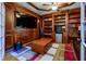 Wood-paneled office featuring built-in bookcases, a large television, and a colorful area rug at 981 Cranbrook Glen Ln, Snellville, GA 30078