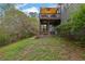 Spacious backyard featuring a deck, patio, green grass, and surrounding trees at 5355 Avonshire Ln, Cumming, GA 30040