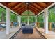 Inviting covered deck featuring wood ceiling, comfortable seating, and forest view at 950 Ivy St, Cumming, GA 30041