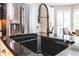 Modern kitchen sink with a stainless steel faucet, black countertop, and stainless steel refrigerator at 3107 Sandhurst Dr, Woodstock, GA 30189