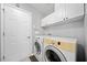 Functional laundry room with modern washer, dryer, white cabinets, and neutral gray walls at 3465 Maple Valley Dr, Cumming, GA 30040