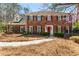 Traditional two-story brick home featuring a manicured front lawn and a welcoming red front door at 9835 Trace Vly, Sandy Springs, GA 30350
