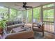 Cozy sunroom with screened windows, neutral furniture, ceiling fan, and view of the wooded backyard at 363 Wilcrest Dr, Lawrenceville, GA 30044