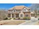 Beautiful brick and stone two-story home with a covered porch, manicured lawn, and a curved driveway at 3149 Hidden Falls Ne Dr, Buford, GA 30519