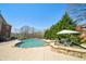 An outdoor swimming pool with tanning ledge and an umbrella sits beside a well-manicured lawn at 3149 Hidden Falls Ne Dr, Buford, GA 30519