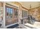 Inviting front porch featuring stone flooring, brick accents, and a charming seating area at 3149 Hidden Falls Ne Dr, Buford, GA 30519