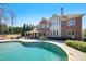 Beautifully landscaped backyard with a swimming pool, covered patio, and brick facade house at 3149 Hidden Falls Ne Dr, Buford, GA 30519