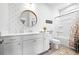 Bright bathroom with white cabinets, a round mirror, patterned wallpaper, and a combined tub and shower at 2121 Hempstead Ct, Snellville, GA 30078