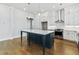Modern kitchen featuring white cabinets, a navy blue island with white countertop, and stainless steel appliances at 630 Silva St, Cumming, GA 30040