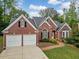 Charming red brick home featuring a two-car garage, manicured lawn, and a brick walkway leading to the front door at 2121 Whitekirk Nw St, Kennesaw, GA 30152