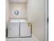 A well-lit laundry room with white washer and dryer, tiled floor and a round window at 2121 Whitekirk Nw St, Kennesaw, GA 30152