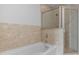 Bathtub and shower combination with glass doors, tiled walls, and stone border at 855 Peachtree Ne St # 2403, Atlanta, GA 30308
