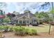 Rear view of the house with expansive windows, stone patio, lush lawn, and mature trees at 803 Amerden Ponds Ct, Johns Creek, GA 30097