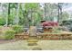 Beautifully landscaped backyard with stone steps, urns, lush trees, and vibrant flowering plants at 803 Amerden Ponds Ct, Johns Creek, GA 30097