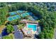 Aerial view of the community pool and amenities with several tennis courts surrounded by mature trees at 803 Amerden Ponds Ct, Johns Creek, GA 30097