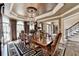 Formal dining room with a chandelier, tray ceiling, large windows, and elegant décor for sophisticated gatherings at 803 Amerden Ponds Ct, Johns Creek, GA 30097