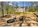 Backyard with fire pit and Adirondack chairs, surrounded by trees and a glimpse of the house at 263 Keller Dr, Mcdonough, GA 30252