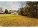 Wide view of back exterior and large lawn featuring trees along the perimeter at 4440 Cannon Rd, Loganville, GA 30052