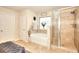 Bright bathroom featuring a soaking tub under a window and a glass enclosed shower with neutral toned tile surround at 910 Shannon Mist Dr, Loganville, GA 30052