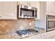 Kitchen with gas stovetop, stainless steel microwave and oven, white cabinets, and granite countertops at 910 Shannon Mist Dr, Loganville, GA 30052