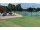 Community playground area with colorful play structures and a fenced tennis court in the background at 910 Shannon Mist Dr, Loganville, GA 30052