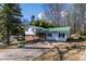 View of the home with a green roof, driveway, and a mix of brick and white siding at 6225 Pebble Dr, Douglasville, GA 30135
