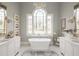 Luxurious bathroom with a standalone tub, chandelier, decorative windows, and dual vanities creating a spa-like retreat at 1100 Muirfield Ct, Alpharetta, GA 30005