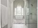 Elegant bathroom with a standalone tub under an arched decorative window, chandelier, and glass shower at 1100 Muirfield Ct, Alpharetta, GA 30005