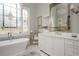 Bright bathroom featuring a standalone tub, marble countertops, dual sinks, and decorative window accents at 1100 Muirfield Ct, Alpharetta, GA 30005